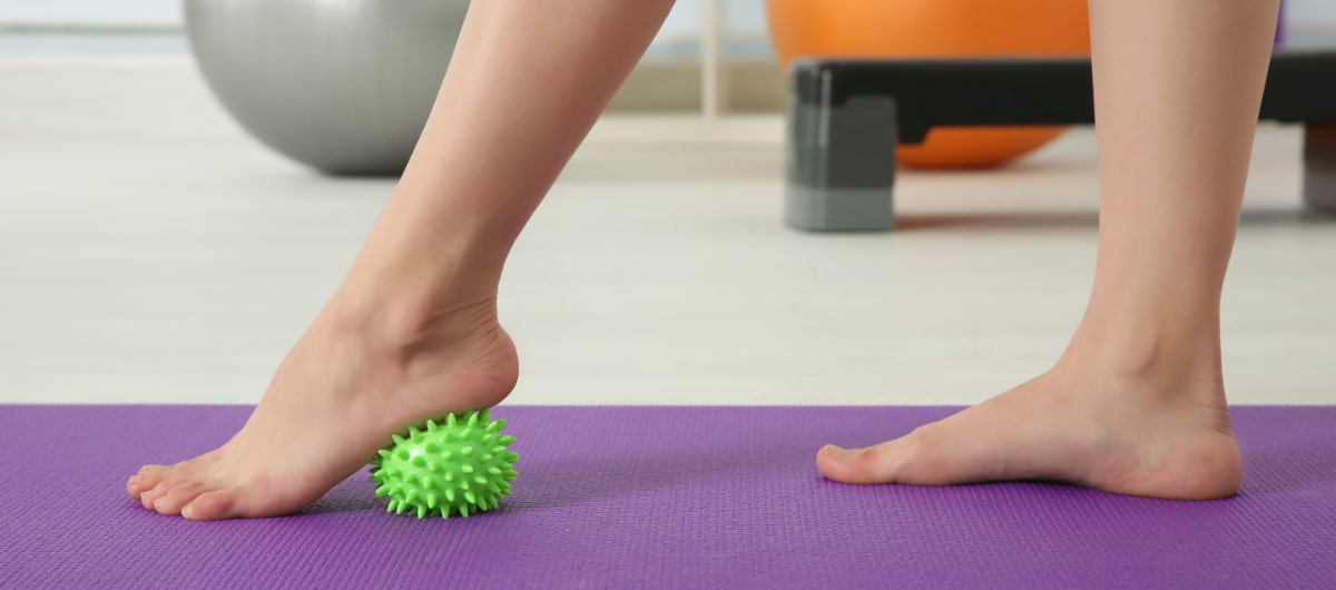Woman using spiked ball, physical therapy for feet
